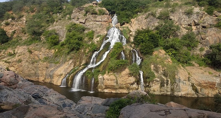 The stunning Chunchi Falls features water cascading down a rugged cliff into a tranquil pool below.