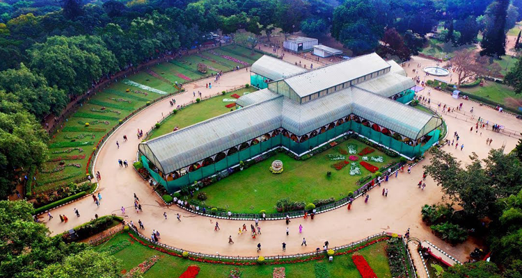 The iconic Glass House in Lalbagh Botanical Garden, surrounded by lush greenery & pathways.