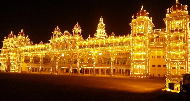 The Mysore Palace glows brightly against the night sky, highlighting its intricate architecture.
