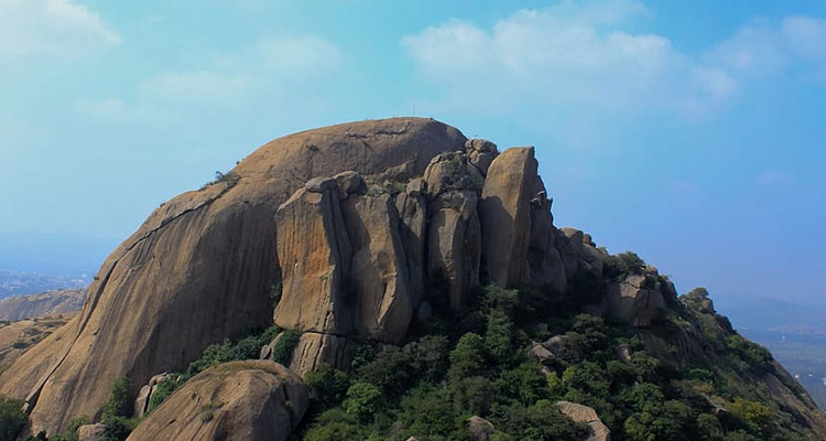 The towering rock formations of Ramanagara stand out against a clear sky, offering a stunning view.