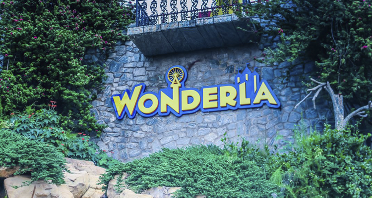 Wonderla Amusement Park stone wall entrance with logo & greenery in a scenic setting.