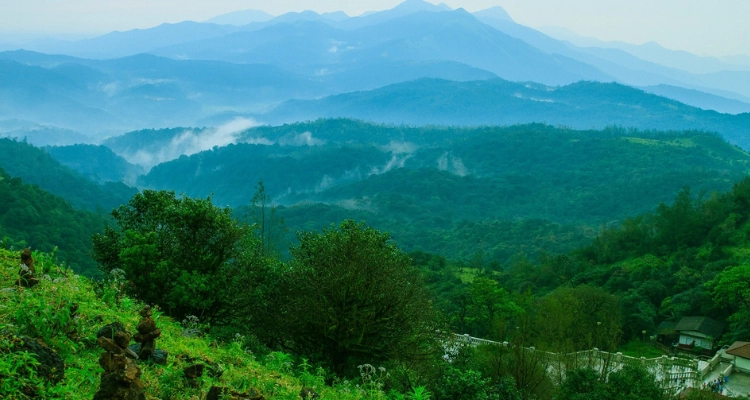 A breathtaking view of green hills and mist-covered mountains offering a serene natural landscape.